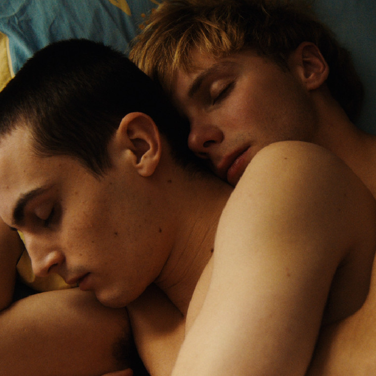 Two young men lying in bed in an embrace