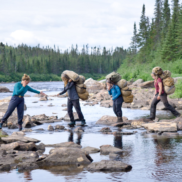 4 women walking across a river via stepping stones 4 women walking across a river via stepping stones
