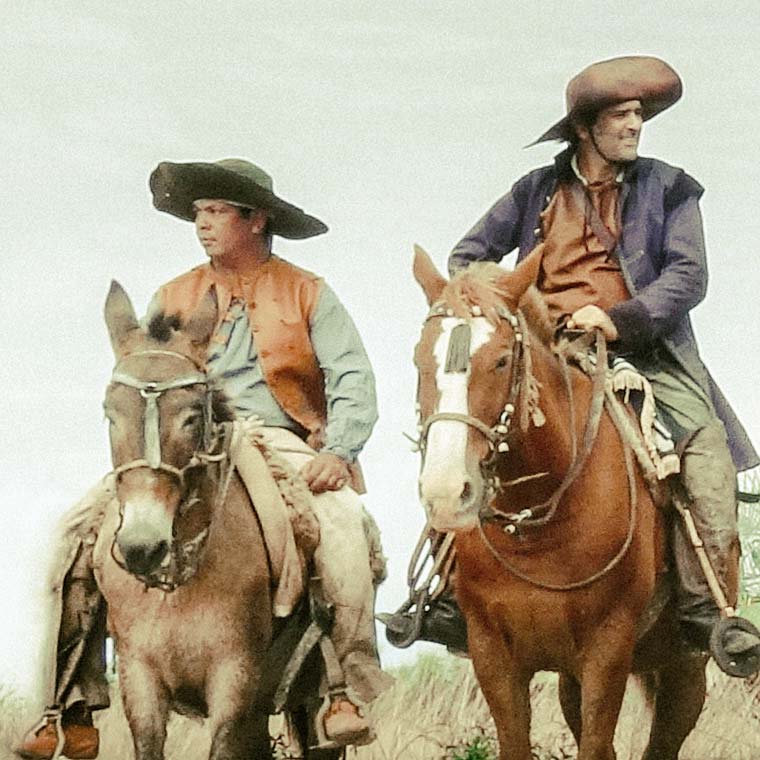 Two cowboys on horses in desert