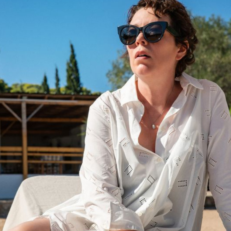 Woman sits by a pool in sunshine