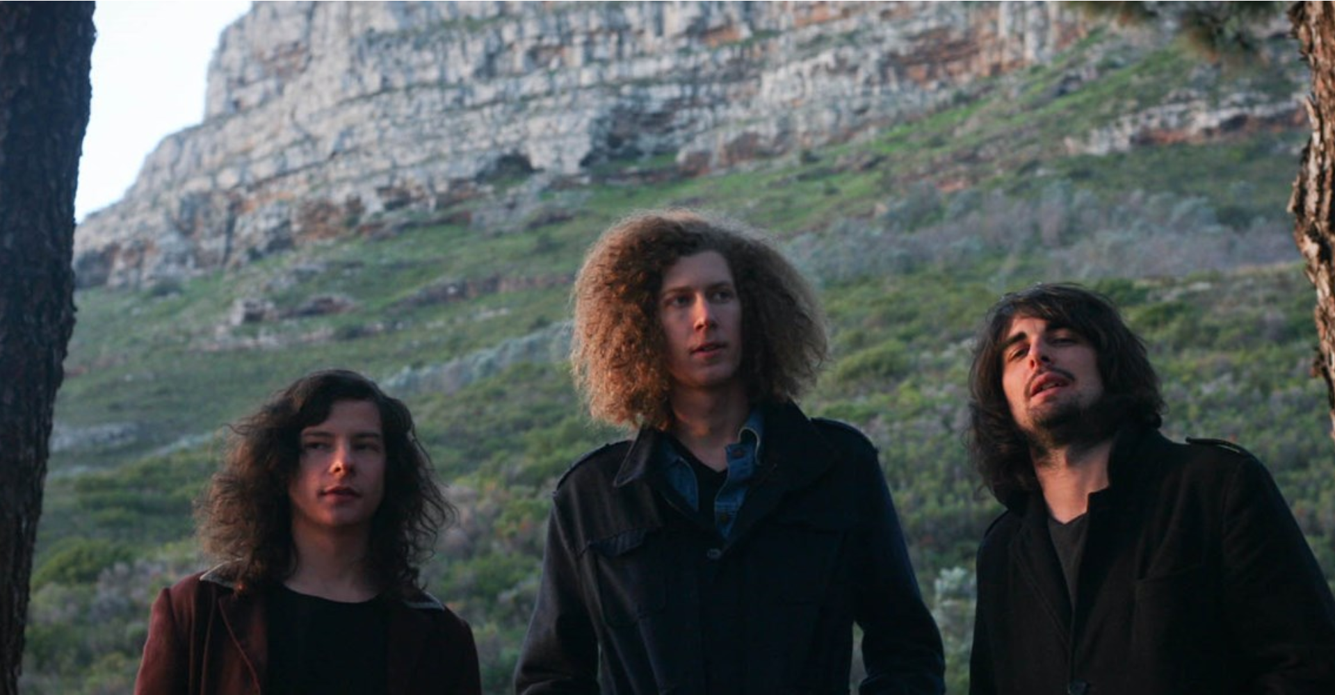 three young men standing in countryside