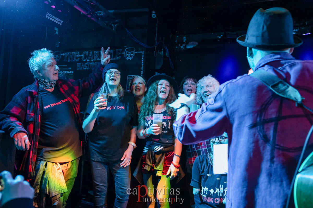 Group of people singing on stage dressed in black