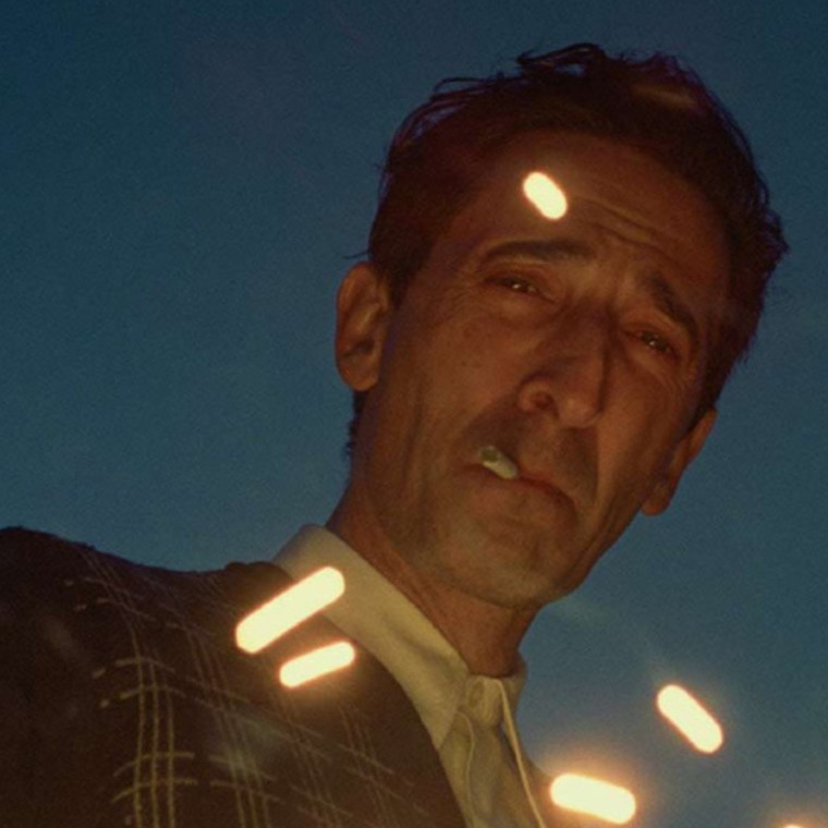 Adrien Brody looking down with sparks near his face